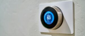 gray Nest thermostat displaying at 63 pompa ciepła czy kocioł elektryczny