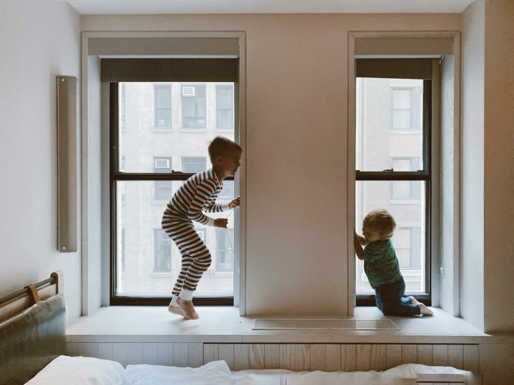 Two Kids Playing Beside Glass Windows czyste powietrze wymiana okien