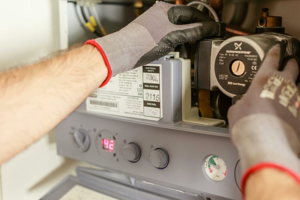 Close-up of hands adjusting a boiler system with precise instrumentation, showing maintenance work. Ile kosztuje ogrzewanie gazowe