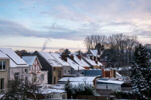 Charming winter scene of snow-blanketed houses in a suburban area with a serene dawn sky.